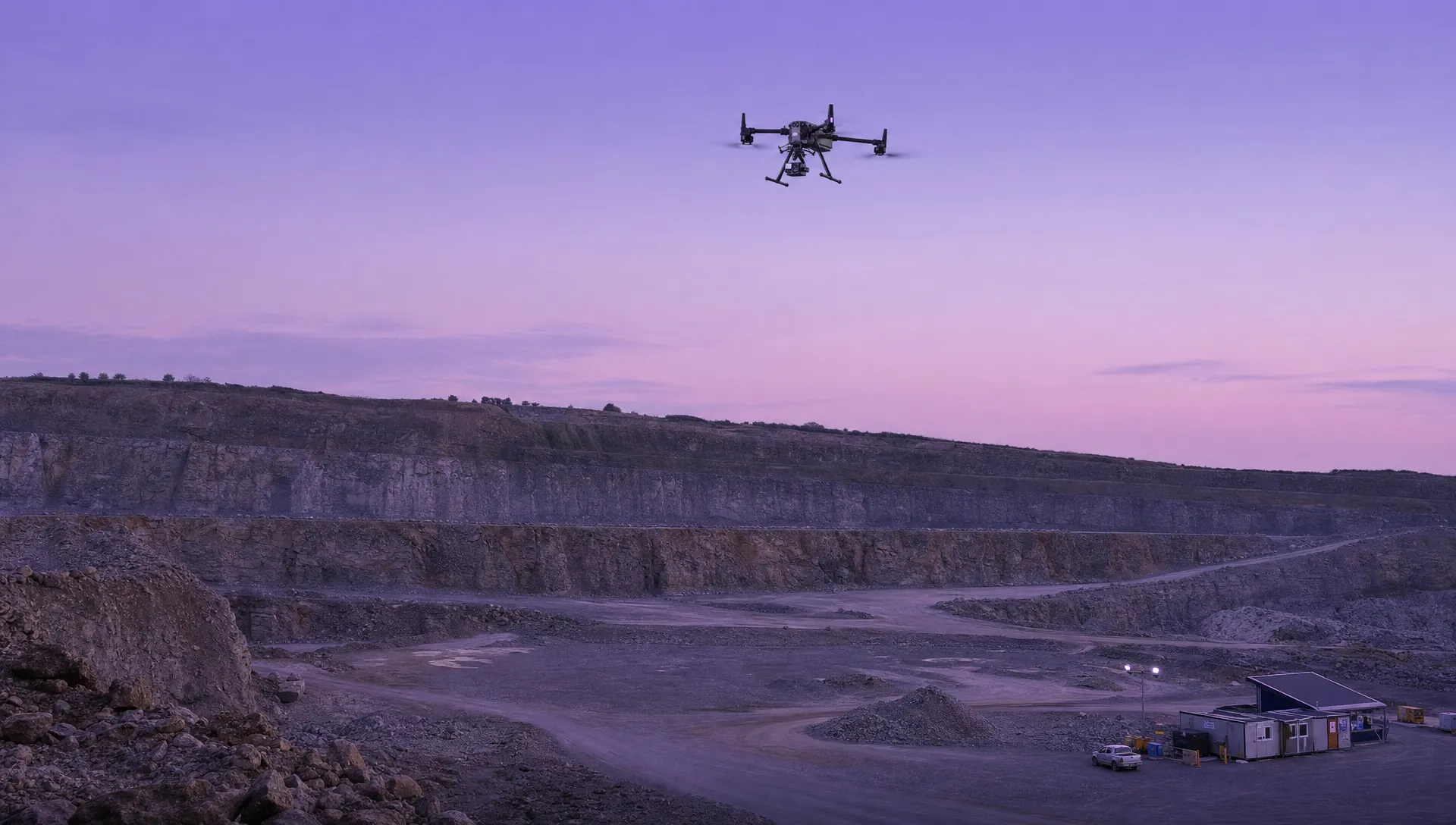 A quarry inspection site shows a drone high above an empty bench with the compound and haul road below.